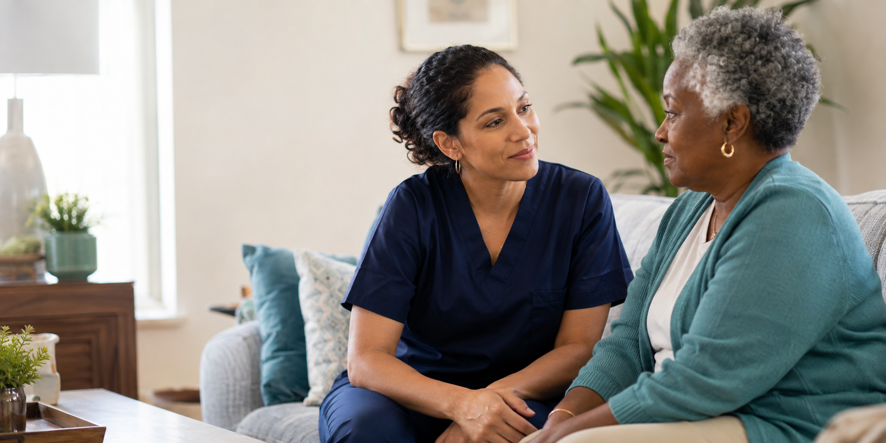 A home care nurse listening attentively to an older adult in her living room